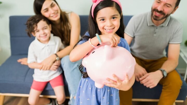 Retrato de uma menina bonitinha colocando dinheiro em um cofrinho rosa para economizar um novo brinquedo para ela e seu irmao pequeno